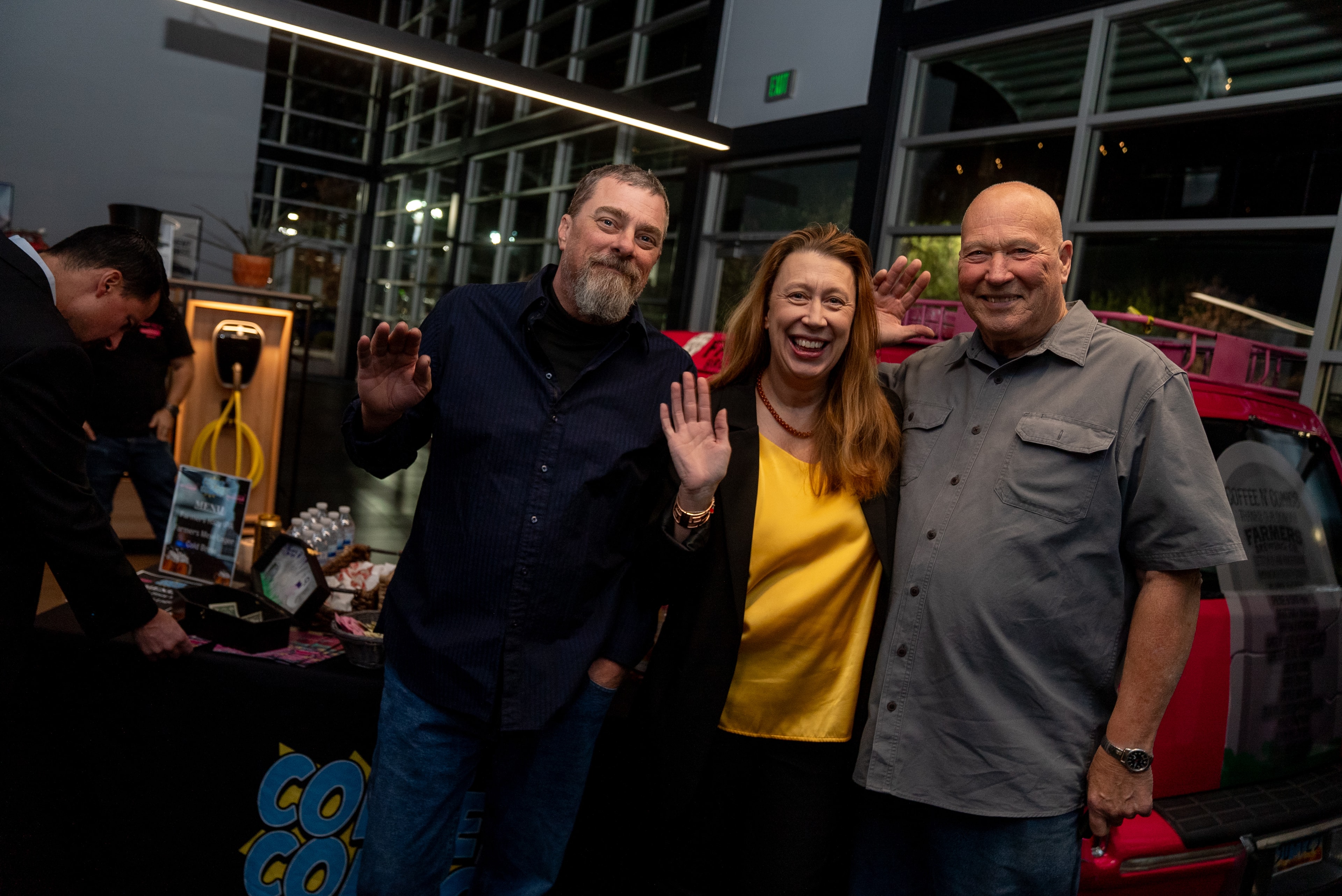 Three people waving at the 2024 event