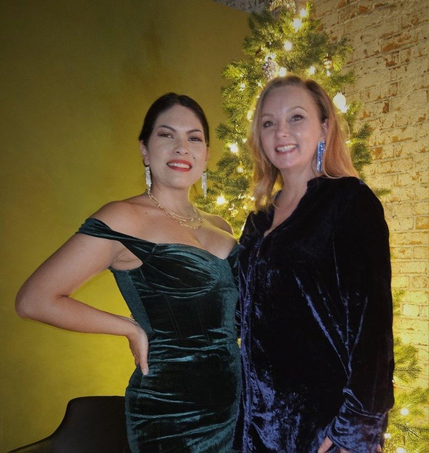 Two women posing holiday garland backdrop