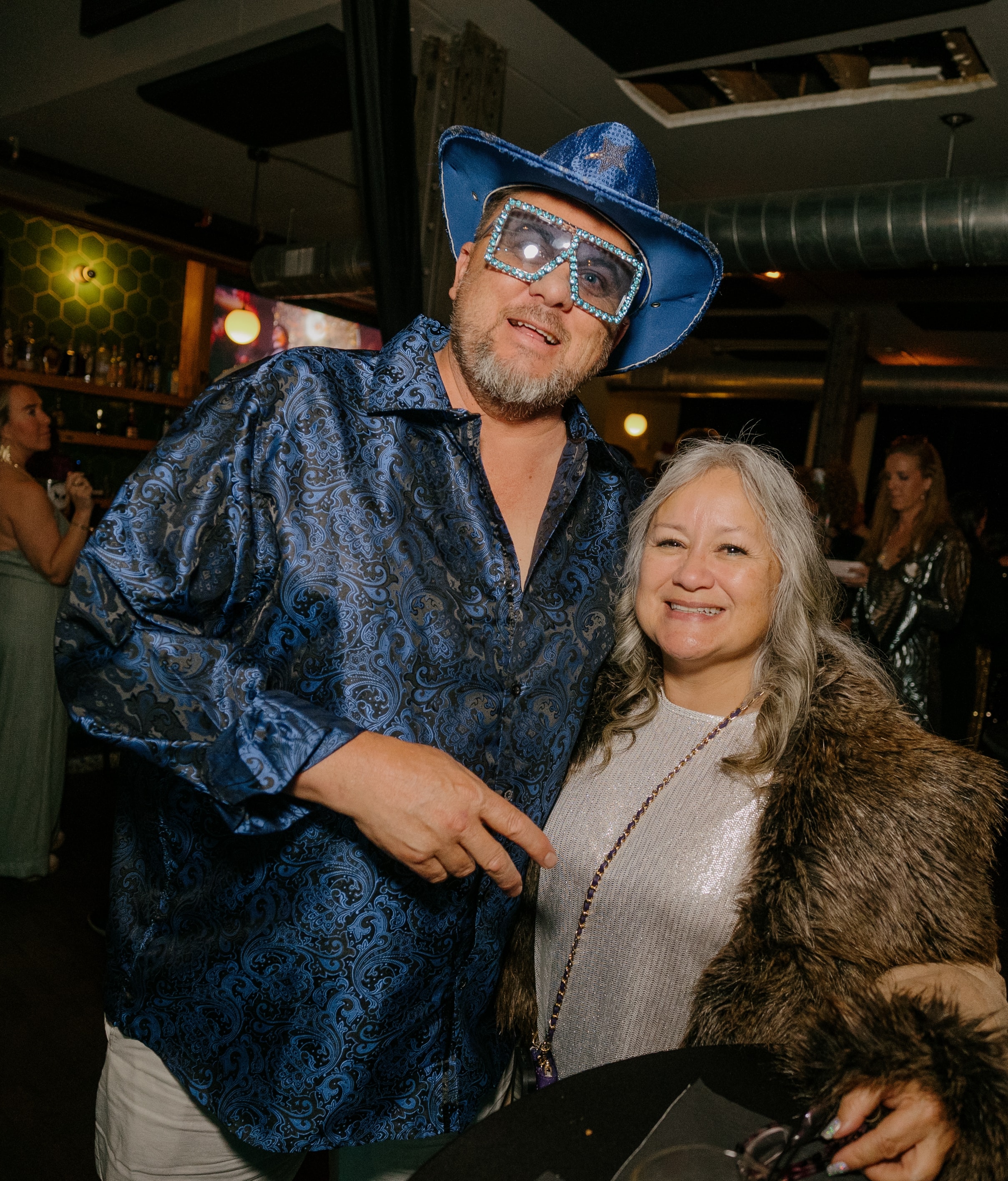 Man in blue cowboy outfit poses with woman