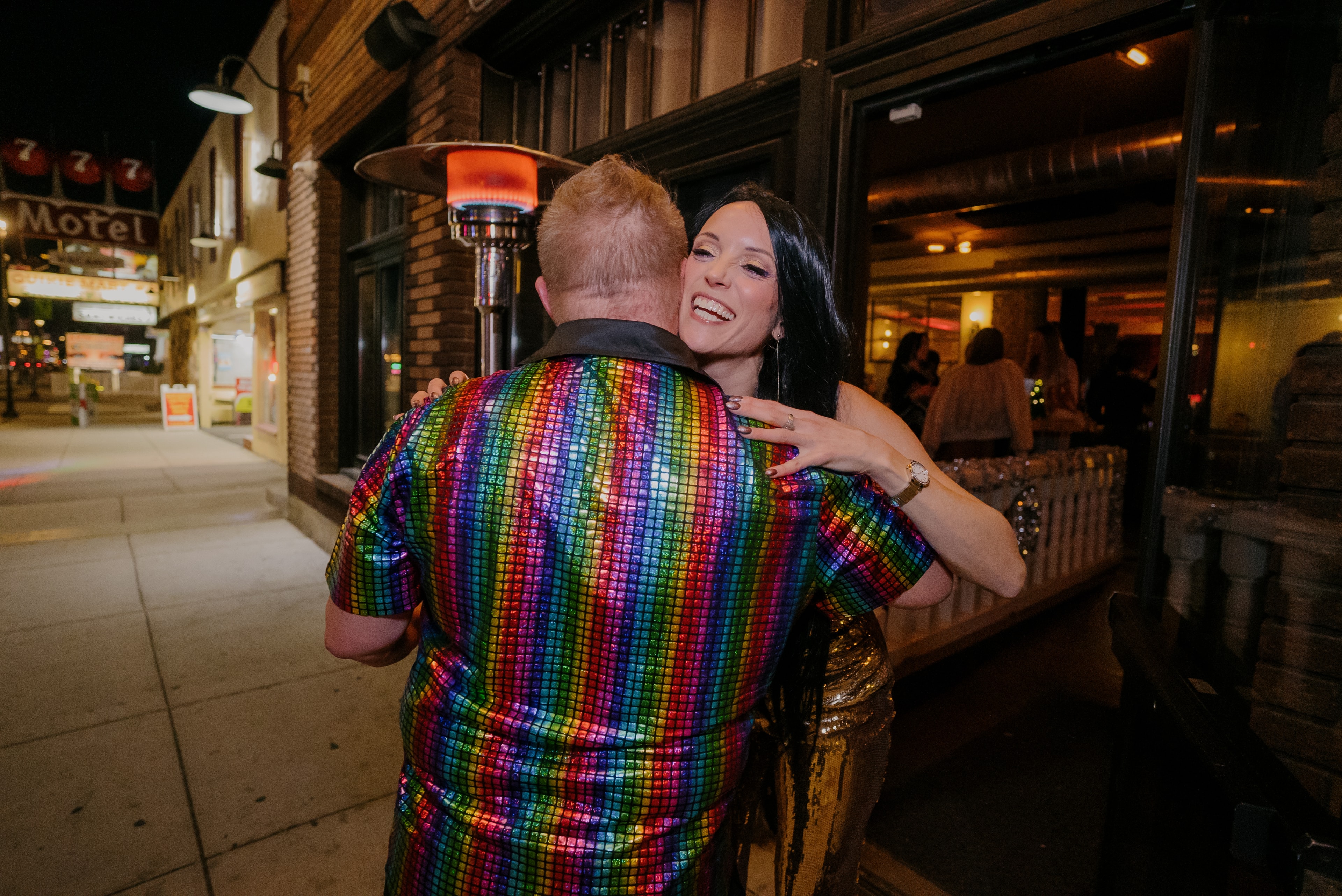 Woman hugging man in rainbow sequin jacket